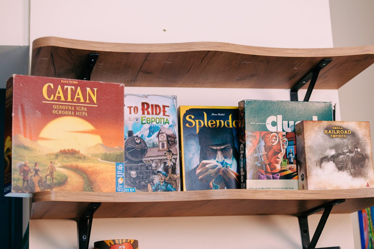 Board games on the shelf at RABOTEKA: Catan, Ticket to Ride, Splendor, Cluedo